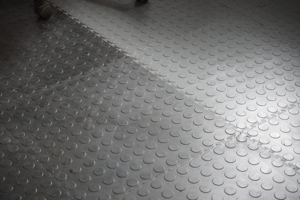 Close-up of recycled PVC garage floor tiles showing raised disk surface texture and interlocking edges